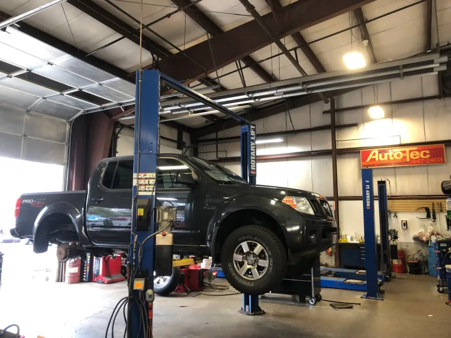 A pickup truck raised on a lift in the Auto Tec service bay